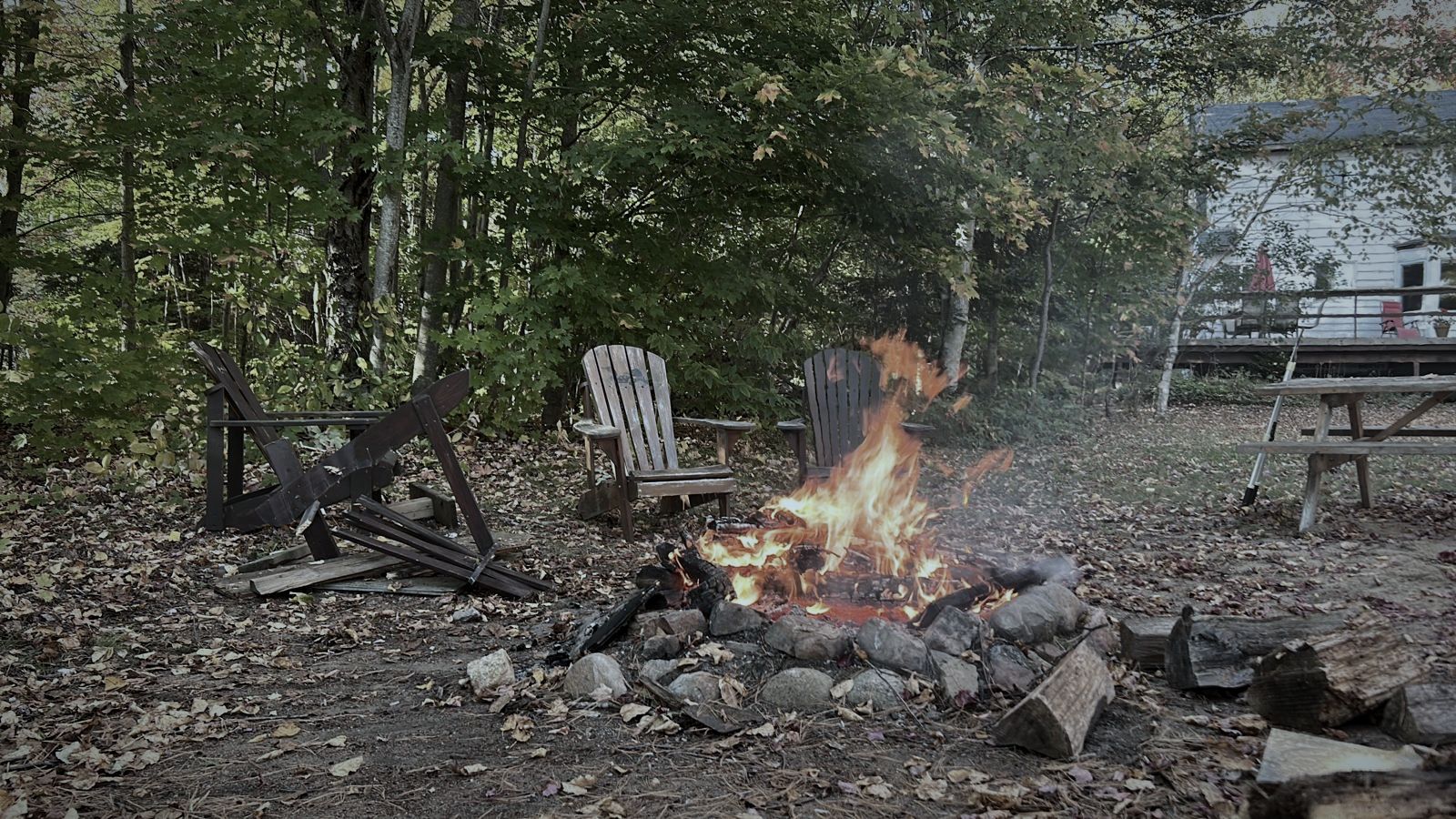 A fire burning in a stone pit surrounded by Muskoka chairs
