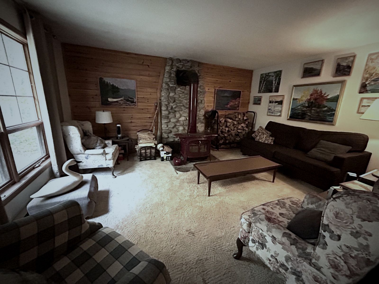 Wood-panelled living room with a wood stove and sofas